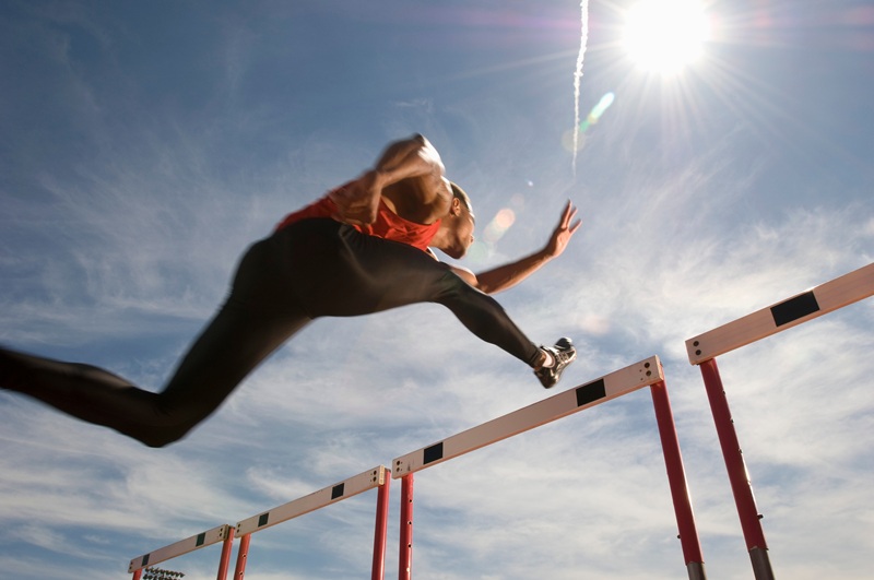 Runner jumping over running hurdle, low angle view